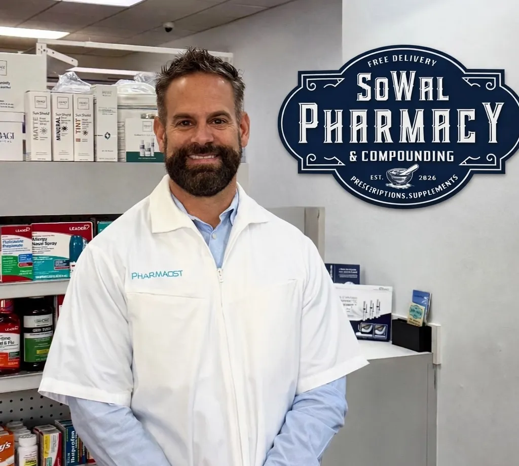 A male pharmacist stands in front of shelves and a sign that reads "SoWal Pharmacy & Compounding.