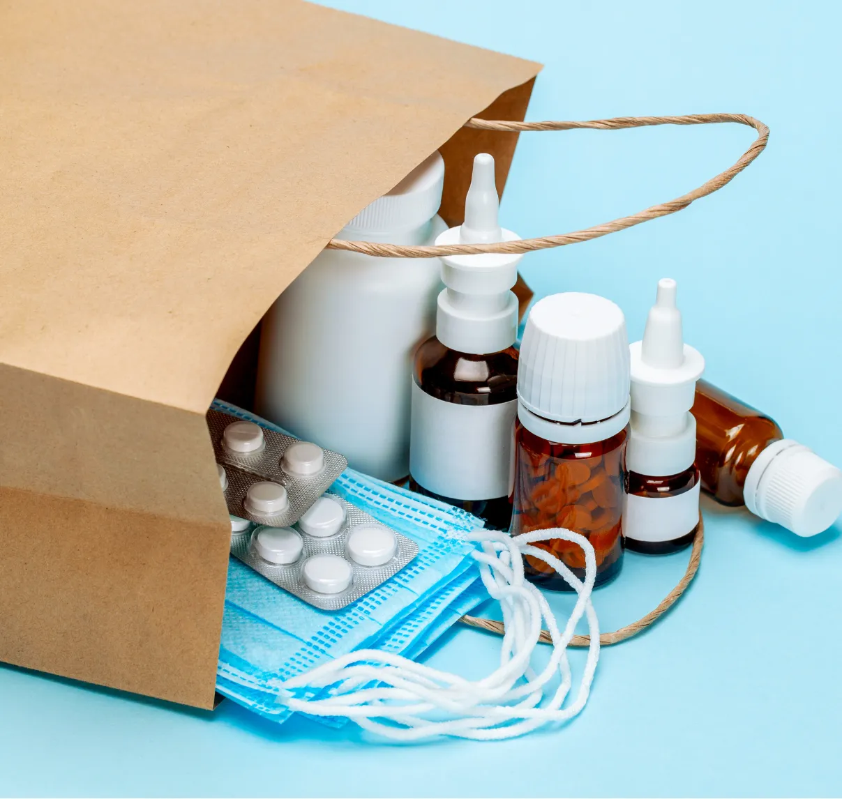 Medical supplies, including masks, pill blister packs, and medicine bottles, spilling from a paper bag on a blue background.