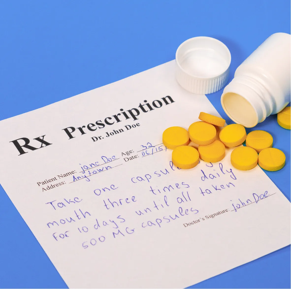 A prescription with yellow pills and a white bottle on a blue surface.
