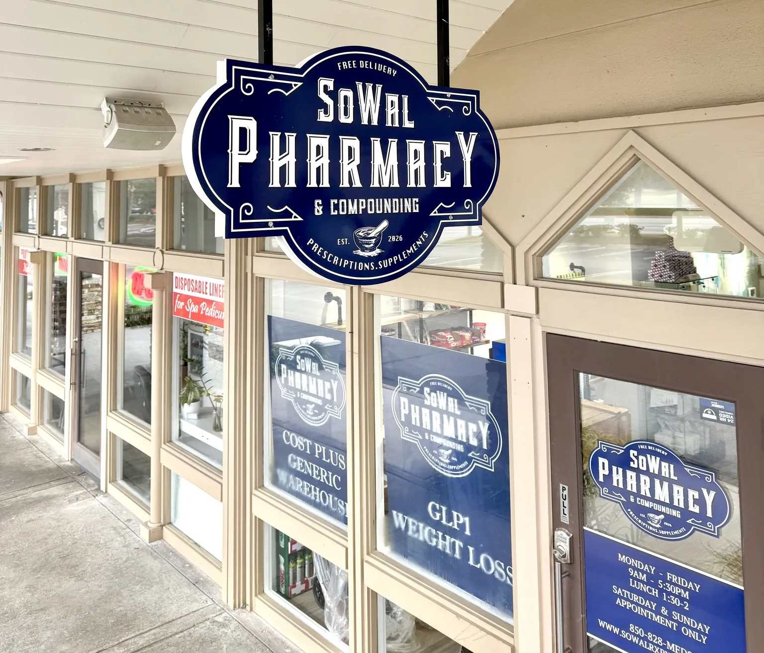 Storefront of SoWal Pharmacy & Compounding with large blue signs and glass windows reflecting light.