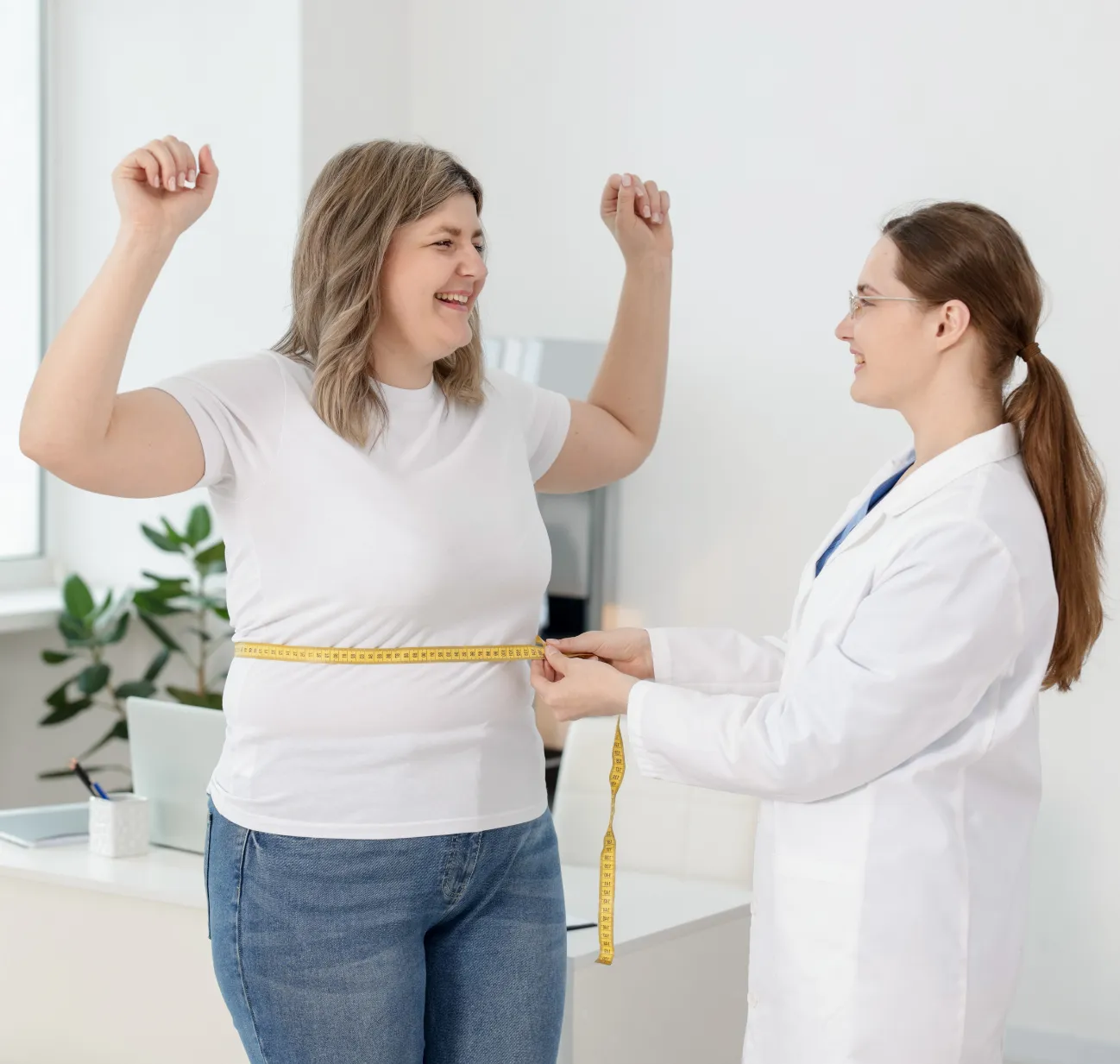 A woman smiles as a healthcare professional measures her waist with a tape measure in a bright office.